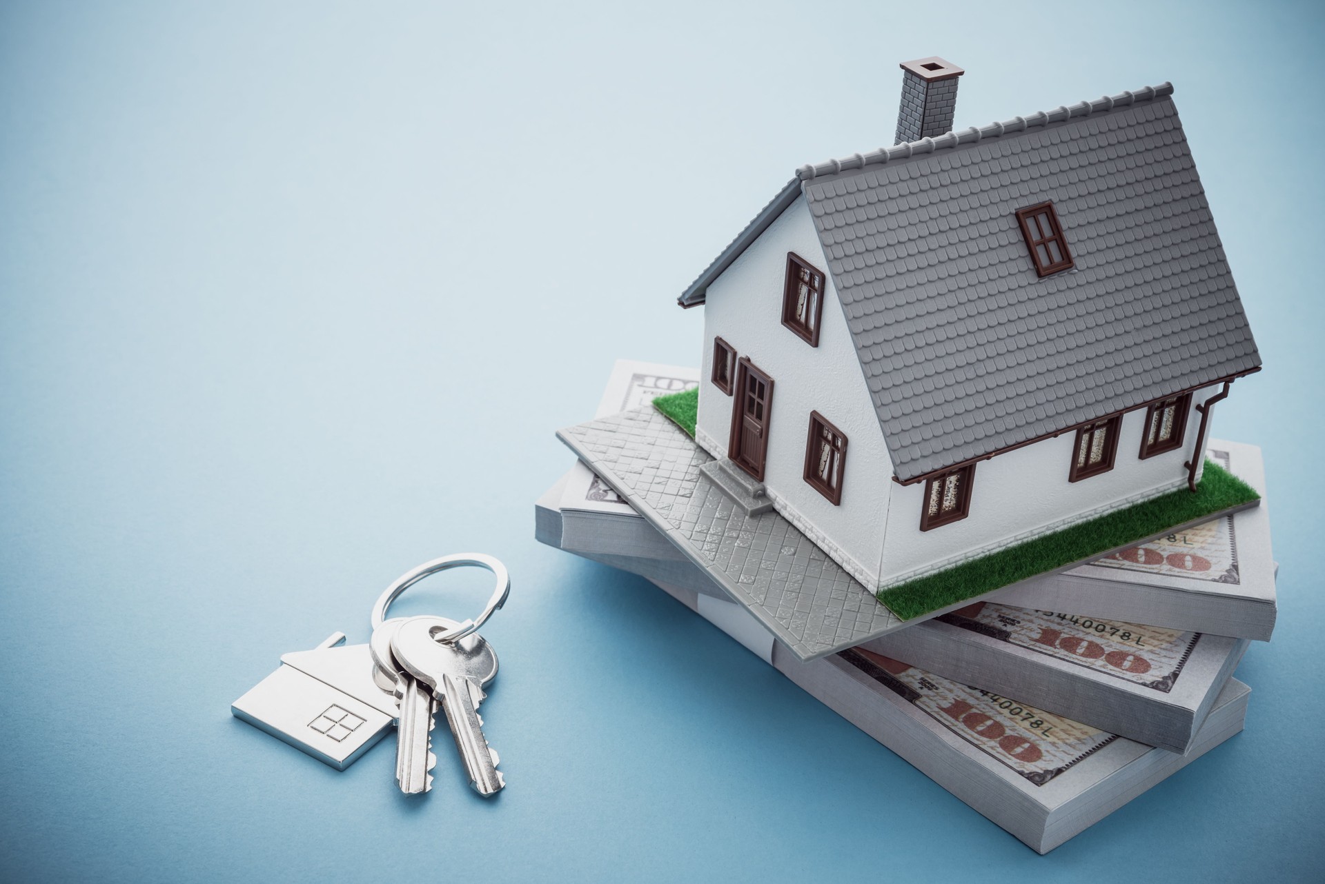 House model, bill dollar banknotes and key on blue background.