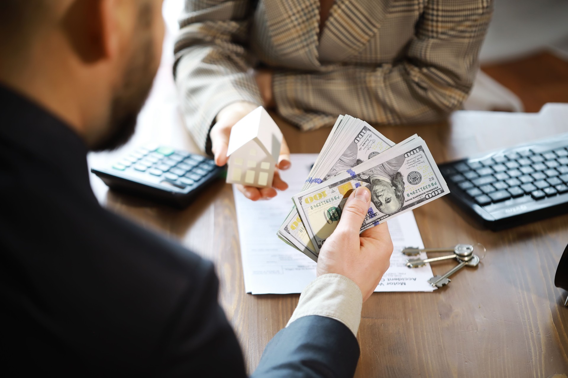 European businesswoman working in real estate company. She is giving cash money to male customer.